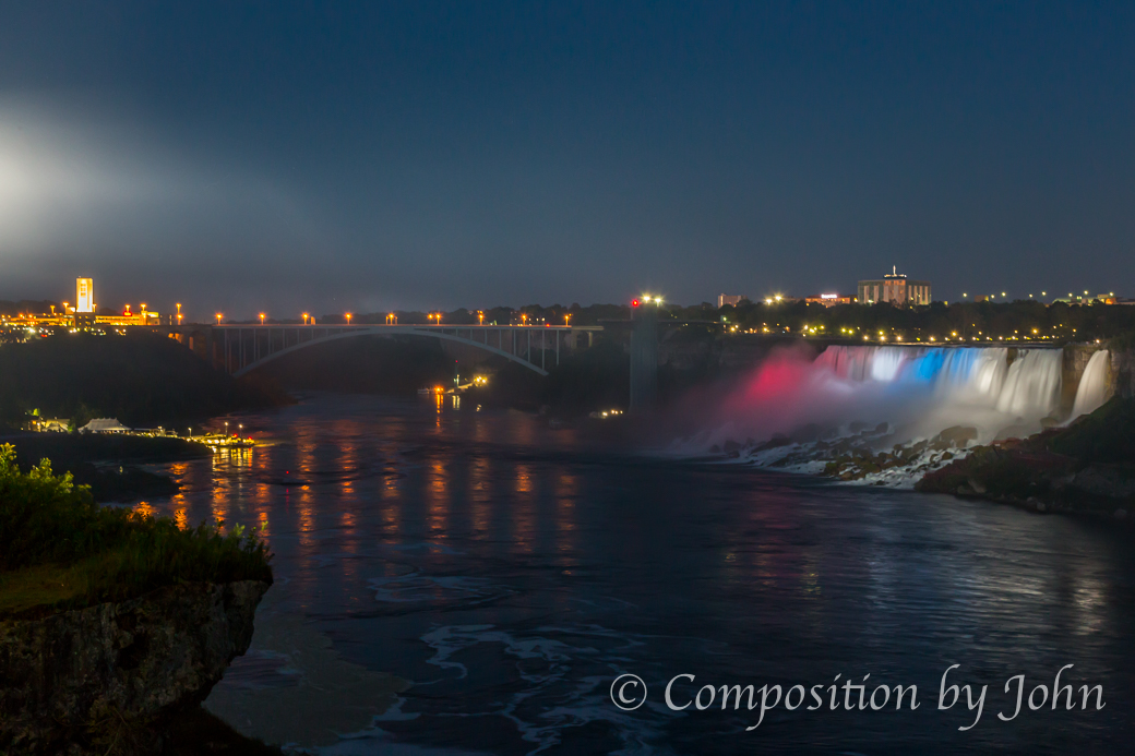American and Bridal Veil Falls lit up at night with the Rainbow Bridge.